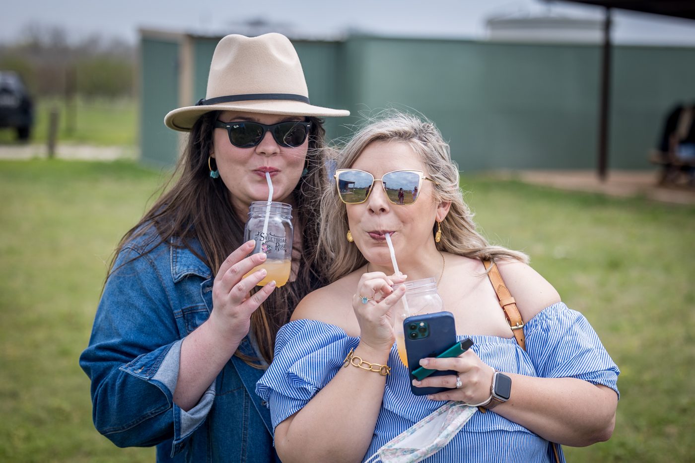 Two guests in sun hats sipping frozen wine on the lawn